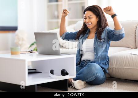 Woman Sitting on Floor in Front of Laptop, Celebrating Success Stock Photo