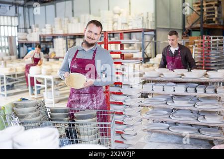 Enthusiastic ceramicist demonstrating handcrafted plates in ceramic studio Stock Photo