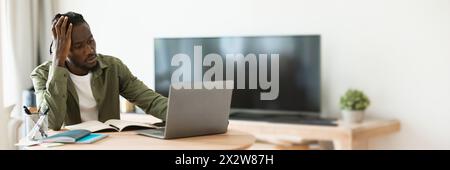 Thoughtful black man using laptop computer at home office Stock Photo