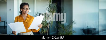 Happy african american businesswoman checking financial papers in office Stock Photo