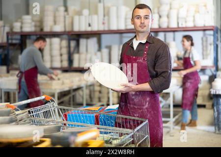 Successful potter displaying handcrafted plate in artisanal studio Stock Photo