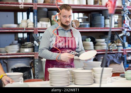 Potter removing dust from ceramics using air gun in workshop Stock Photo