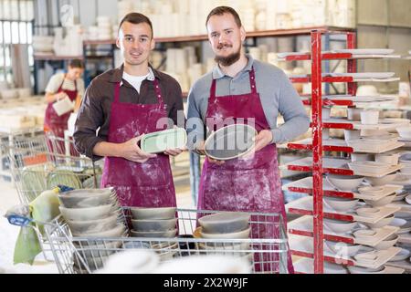 Two potters holding handcrafted ceramic plates in pottery workshop Stock Photo