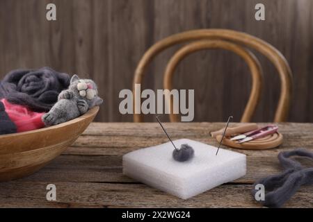 Felting tools, wool and toy cat on wooden table Stock Photo