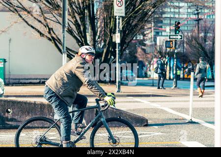 A man riding a road bike in the bike lane stopped at a traffic light at the intersection of Dunsmuir and Citadel Parade streets. Stock Photo