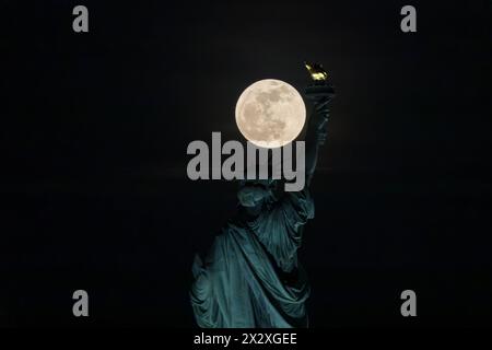 Jersey City, United State. 23rd Apr, 2024. The Pink Moon, illuminated at 100 percent, rises behind the Statue of Liberty in New York City on April 23, 2024. Credit: Brazil Photo Press/Alamy Live News Stock Photo