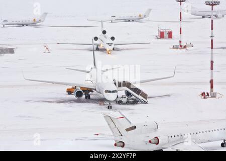 Airplanes and serving machinery on snowy airfield. Stock Photo
