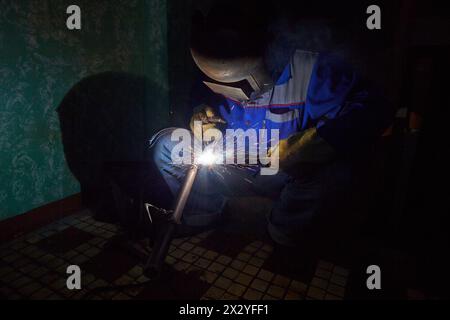 Wekder in protective suit and mask welds metal details Stock Photo