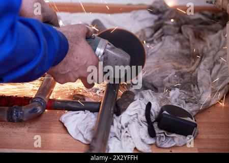 Male hands cuts off piece of water pipe with angle grinder Stock Photo