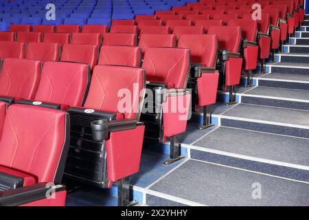 Rows of red and blue seats and stairs in auditorium in cinema theater. Stock Photo