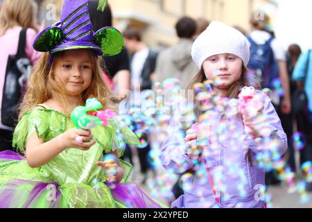 Two little girls blow a lot of soap bubbles in the street on the holiday of spring and bubbles Dreamflash Stock Photo