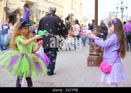 Two little girls blow a lot of soap bubbles in the street on the holiday of spring and bubbles Dreamflash Stock Photo