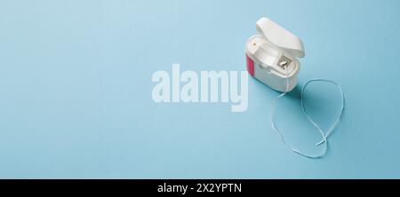 Top view of dental floss in white box on blue background Stock Photo