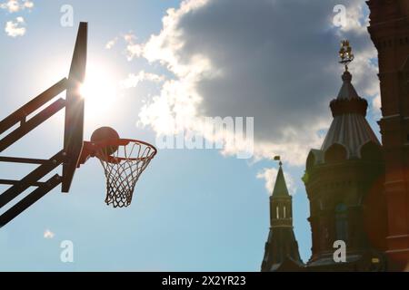 A silhouette of a basketball ball in the basket against the sky, the clouds and the Kremlin. Stock Photo