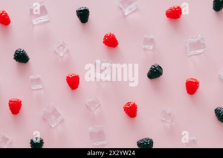 Creative summer pattern made of raspberries, blackberries and ice cubes on light pink background. Fruit minimal concept. Trendy healthy food pattern. Stock Photo