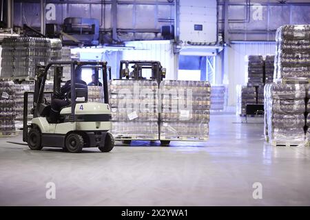 MOSCOW - MAY 31: Workers on loader machines in storage of Ochakovo factory, on May 31, 2012 in Moscow, Russia. Moscow factory of Ochakovo company prod Stock Photo