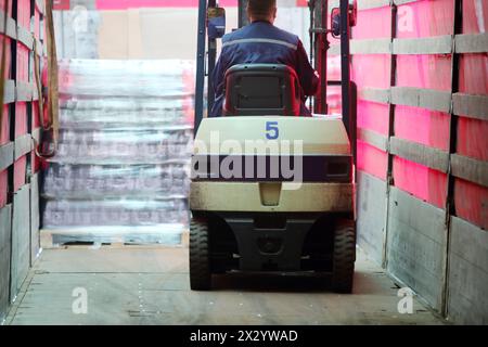 MOSCOW - MAY 31: Back of man working on loader machine in Ochakovo factory, on May 31, 2012 in Moscow, Russia. Moscow factory of Ochakovo company prod Stock Photo
