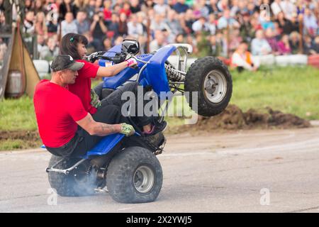 MOSCOW - AUG 25: Man with girl rides on the rear wheels on a quad bike on Festival of art and film stunt Prometheus in Tushino on August 25, 2012 in M Stock Photo