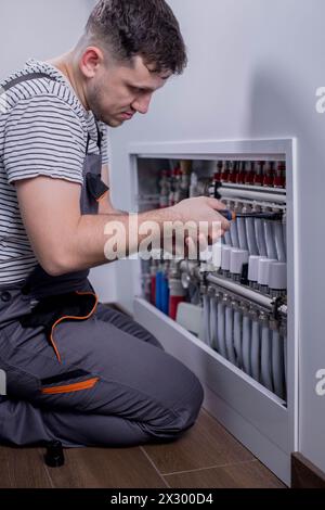 Plumber work. Installing collector for warm water underfloor heating system. Stock Photo