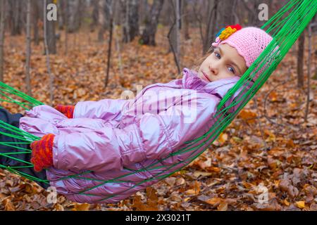 Thoughtful girl swinging in a hammock in the autumn forest Stock Photo