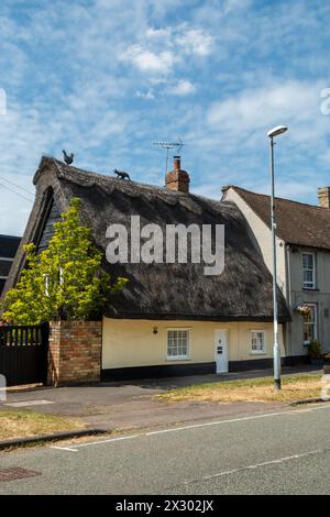 Animal finials on a thatched roof, a cat chasing a hen, and a traditional brick chimney. Great Shelford, Cambridgeshire, England, UK Stock Photo