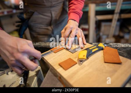 Male hands cutting leather skin. Master shoemaker cobbler professional working with knife. Stock Photo
