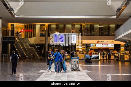 Einige Reisende stehen am Flughafen Zürich im Terminal 1 und orientieren sich. Dahinter das Edelweiss Café und die Swiss Lounge. (Zürich, Schweiz, 16. Stock Photo