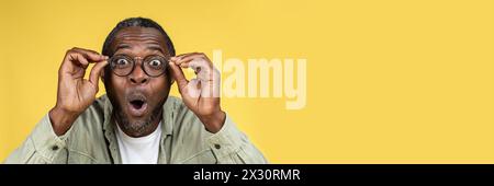 Surprised happy funny excited mature black man adjusting glasses Stock Photo