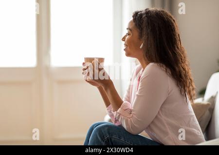 Young Woman Relaxing with Earphones While Seated on Home Sofa Stock Photo