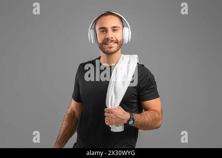 Man Wearing Headphones and Holding Towel On Gray Background Stock Photo