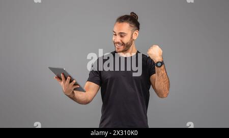 Man in Black Shirt Holding Tablet On Grey Background Stock Photo