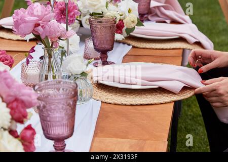 Picnic aesthetics table setting, flowers arrangement. Tabletop with floral decoration and place settings. Dining etiquette and table decor concept. Stock Photo