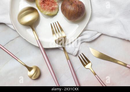 Creative shot of golden cutlery on marble table, Design concept. Modern kitchen. Scandinavian style tableware. Stock Photo