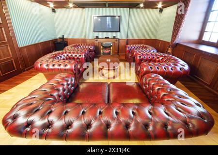 English cigar room with leather armchairs for rest and home theater system. Stock Photo