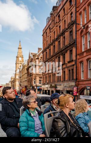 Liverpool, UK, April 11 2024: A group of tourists admire the sights of the city of Liverpool, from a double-decker bus, without a roof, which takes th Stock Photo