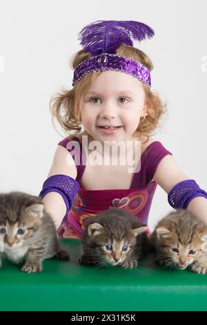 Little girl in costume magician and kittens on the green table Stock Photo