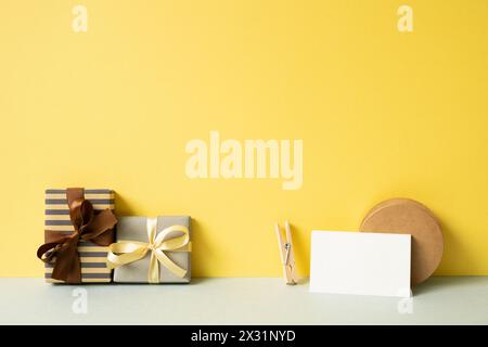 Gift boxes and wrapping accessory on gray desk. yellow wall background Stock Photo