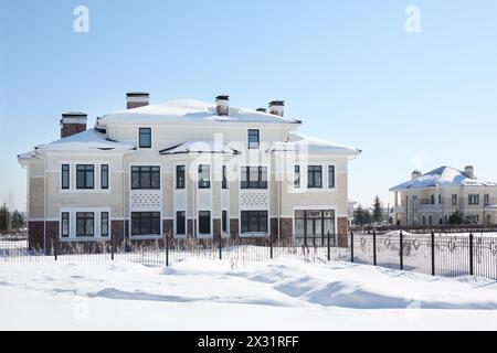 Large two-storey new cottage with big windows on sunny frosty winter day. Stock Photo