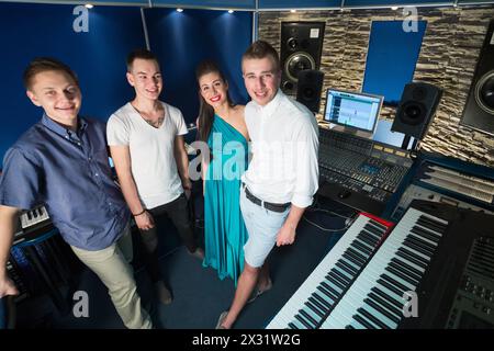 Three smiling guys musician and a girl singer in the Recording Studio with equipment, with property release Stock Photo