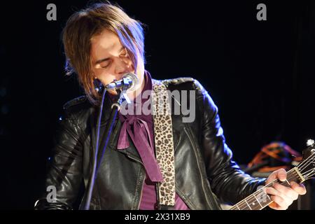 Young singer in leather jacket with closed eyes plays guitar and sings. Stock Photo