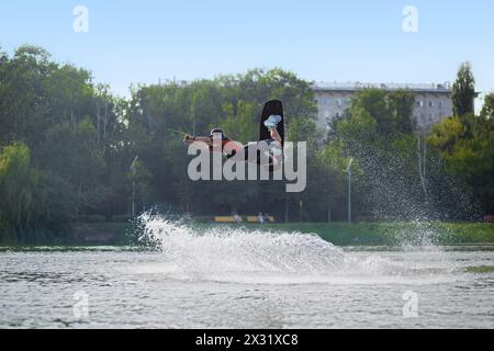 MOSCOW - JUL 13: While wakeboarding man jumping over the waves on a board on the river in Sokolniki on July 13, 2013 in Moscow, Russia. Stock Photo