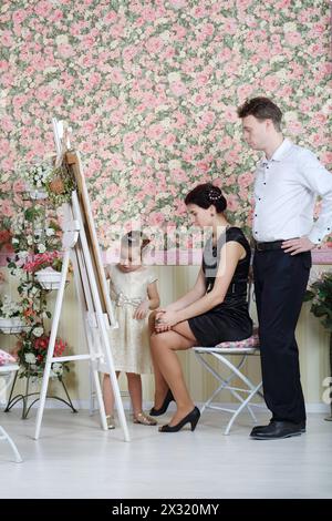 Father and mother look at their painting daughter in beautiful retro interior. Stock Photo