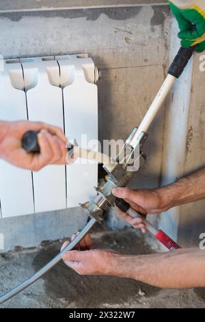 Workers crimping pipe heating system in the apartment Stock Photo