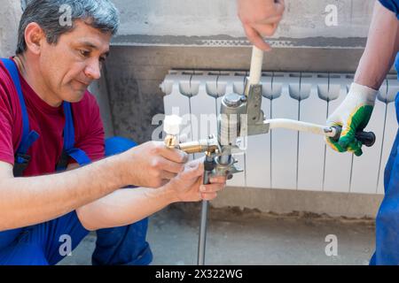Two workers swaged pipe heating system in the apartment Stock Photo