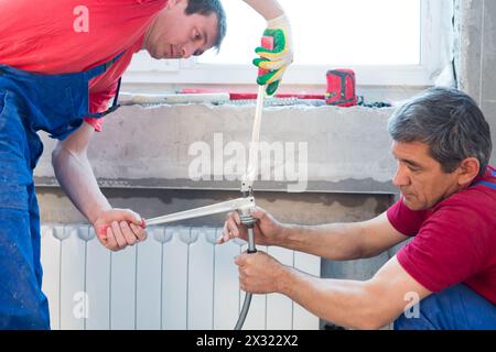 Workers prepare the pipes for the heating system crimping Stock Photo