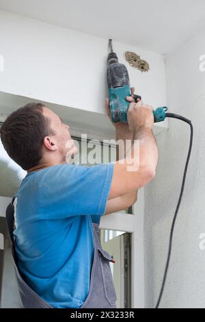 Worker makes a hole in the ceiling using a drill Stock Photo