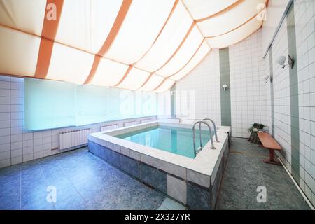 A small indoor pool with tiles on walls and floor and blinds on the windows Stock Photo