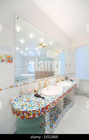 Two sinks and big mirror in spacious bathroom with blue and red tiles. Stock Photo