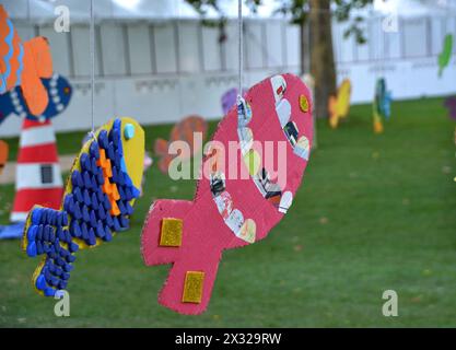 Pink painted cardboard fish hanging from a rope in a playground Stock Photo