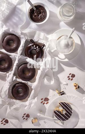 Glazed chocolate donuts and cup of cappuccino on stone background. Top view. Flat lay composition Stock Photo